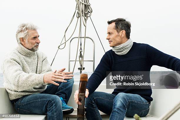 two mature men talking in sailingboat - sailingboat stock-fotos und bilder