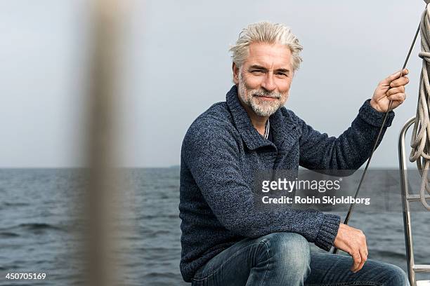 mature grey haired man on board a sailing boat - sea outdoors mature stock-fotos und bilder