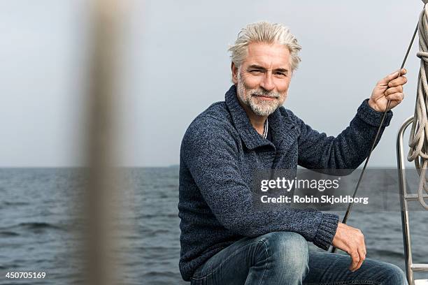 mature grey haired man on board a sailing boat - sweater stockfoto's en -beelden