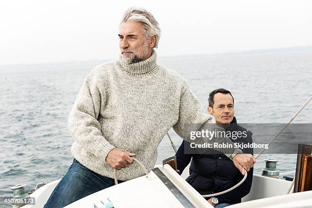 two mature men on sailingboat - sailingboat stock-fotos und bilder