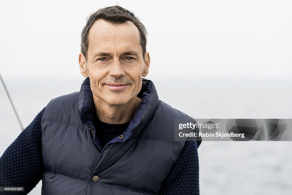 Mature man wearing blue vest smiling