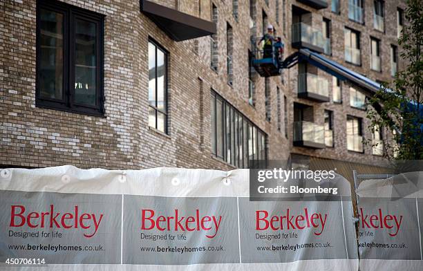 Construction workers stand on a self-drive access platform as they work outside Berkeley Group Holdings Plc's Marine Wharf apartment construction...