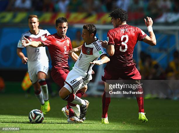 Mesut Oezil of Germany is challenged by Hugo Almeida and Pepe of Portugal during the 2014 FIFA World Cup Brazil Group G match between Germany and...