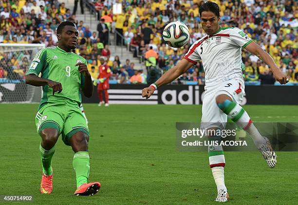 Iran's defender Amir Hossein Sadeqi challenges Nigeria's forward Emmanuel Emenike during the Group F football match between Iran and Nigeria at the...