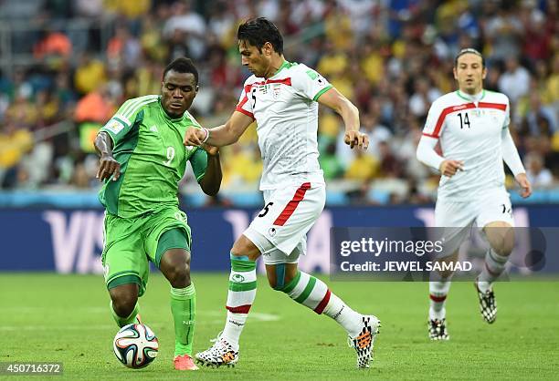 Nigeria's forward Emmanuel Emenike challenges Iran's defender Amir Hossein Sadeqi during the Group F football match between Iran and Nigeria at the...