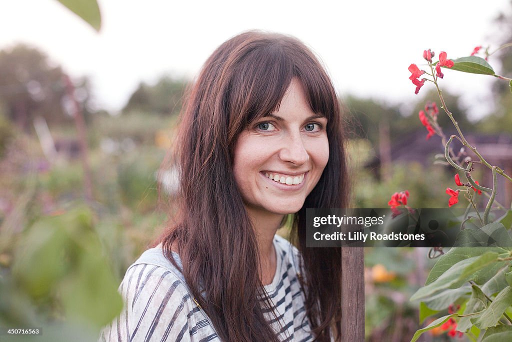 Woman holding hoe and smiling at allotment