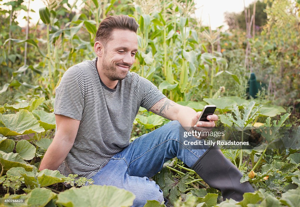 Man texting sat in allotment