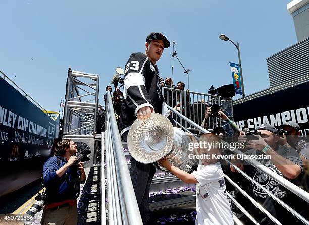 Dustin Brown of the Los Angeles Kings and his son Mason carry the Stanley Cup off the flat bed truck during Los Angeles Kings victory parade and...