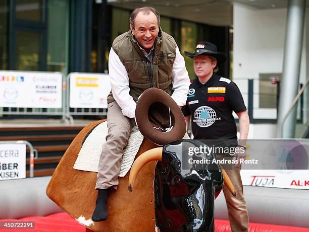 Moderator Wolfram Kons poses on a bull riding machine during a photocall on November 20, 2013 in Cologne, Germany. Joey Kelly will go riding 24 hours...