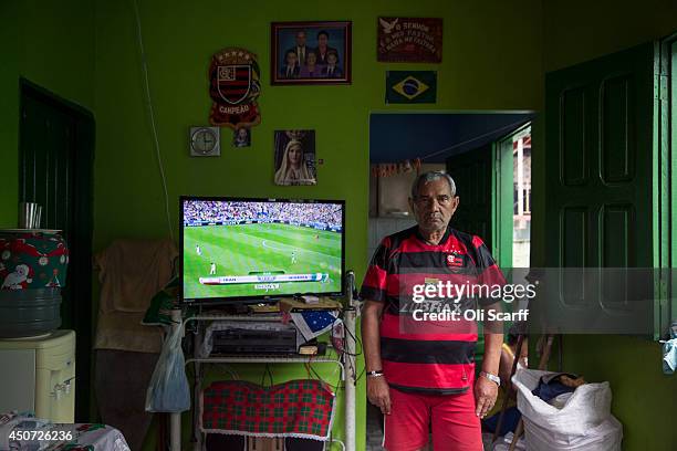 Emmanuel Duarte Pires poses for a photograph at home in a football shirt as he prepares to watch the 2014 FIFA World Cup match between Iran and...