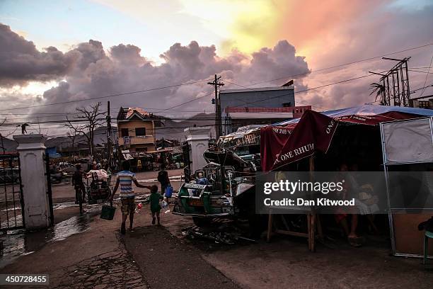 People take shelter under plastic sheets next to the wreck of a bus known locally as a Jeepney outside the Tacloban astrodome evactuatuion centre on...