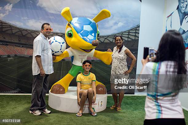Family pose for a photograph with a statue of 'Fuleco', the mascot of the 2014 FIFA World Cup, in the Fan Fest area in Ponta Negra on June 16, 2014...