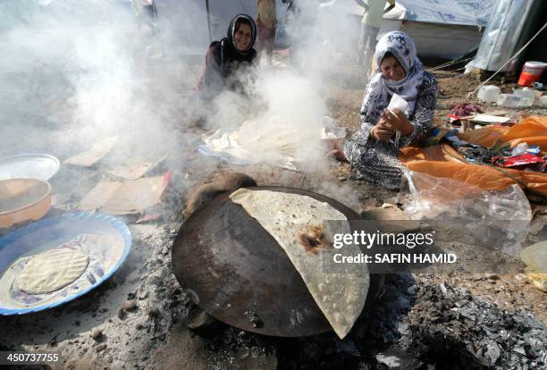 Syrian-Kurdish refugees bake bread on a typical domed metal griddle for baking traditional flat bread, known locally in the region as the saj, at the...