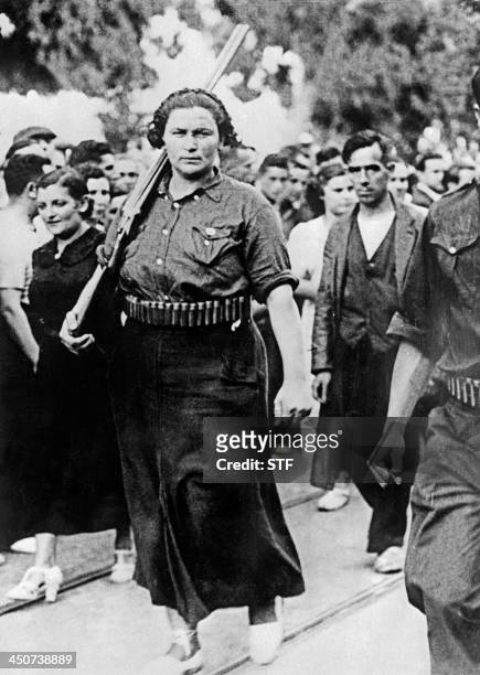 Photo prise dans la seconde moitié des années 30 d'une femme républicaine armée d'un fusil et portant une cartouchière défilant dans une ville non...