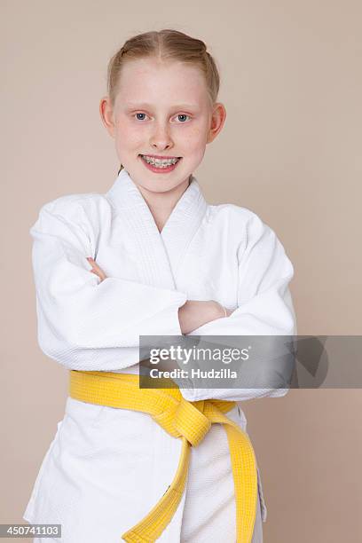 a smiling girl with arms crossed wearing martial arts uniform with yellow belt - 12 13 girl closeup stock pictures, royalty-free photos & images