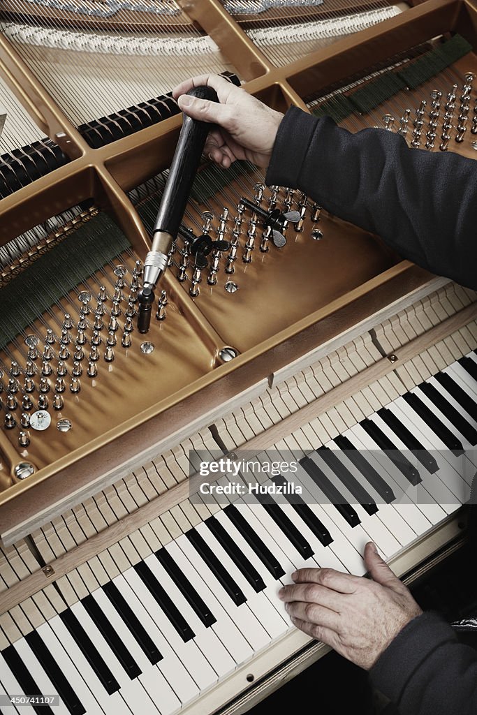 A repairman working on a grand piano