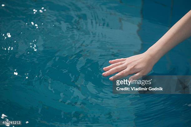 a young girl's hand rippling the water in a swimming pool - testing the water 英語の慣用句 ストックフォトと画像