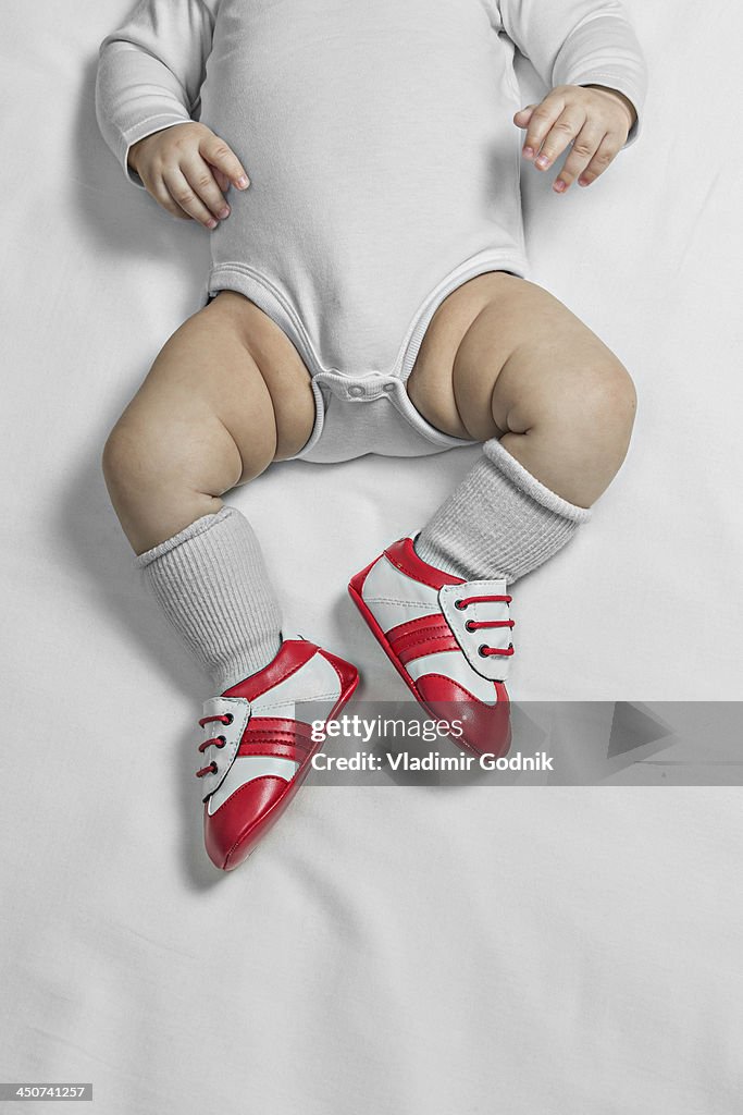 A baby boy wearing baby soccer shoes, waist down