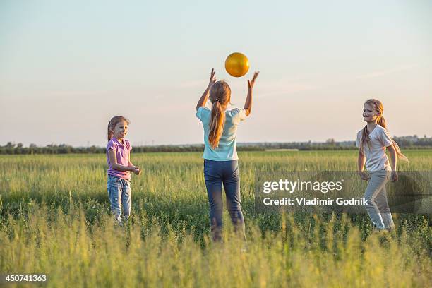 three young girls playing catch in a sunny field in summer - ring toss bildbanksfoton och bilder