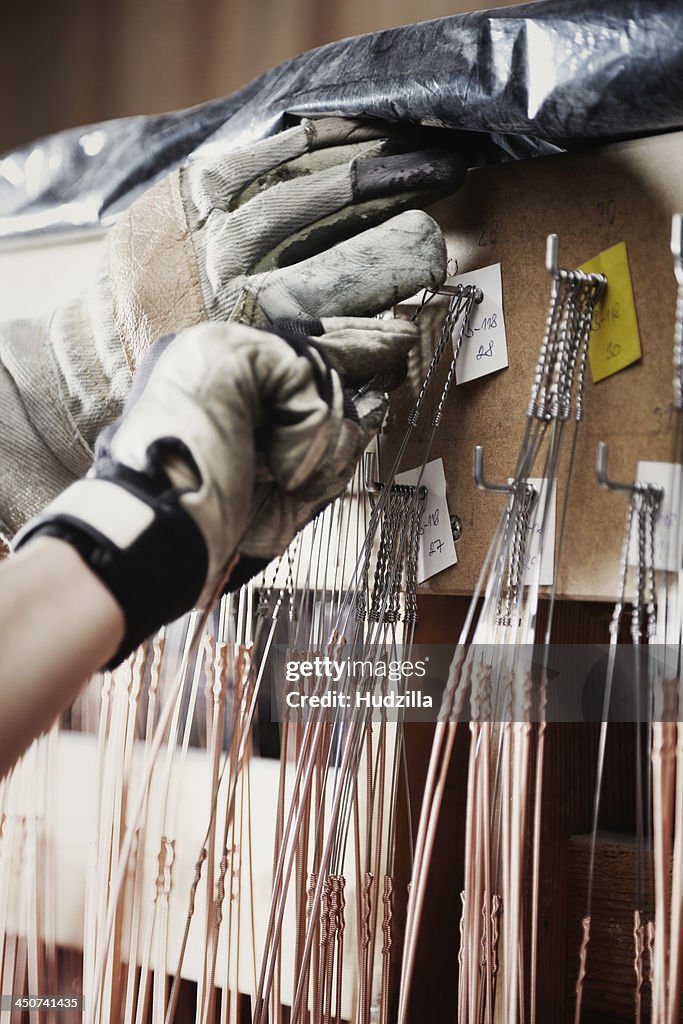 A repairman selecting a string for a piano, close-up of hands