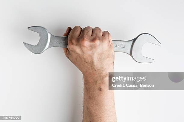 a fist holding a wrench up triumphantly - gripping tool stock pictures, royalty-free photos & images