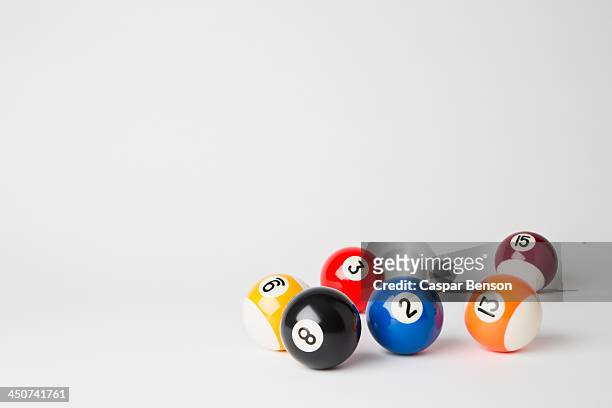 six pool balls, including the eight ball, on a white surface - azar - fotografias e filmes do acervo
