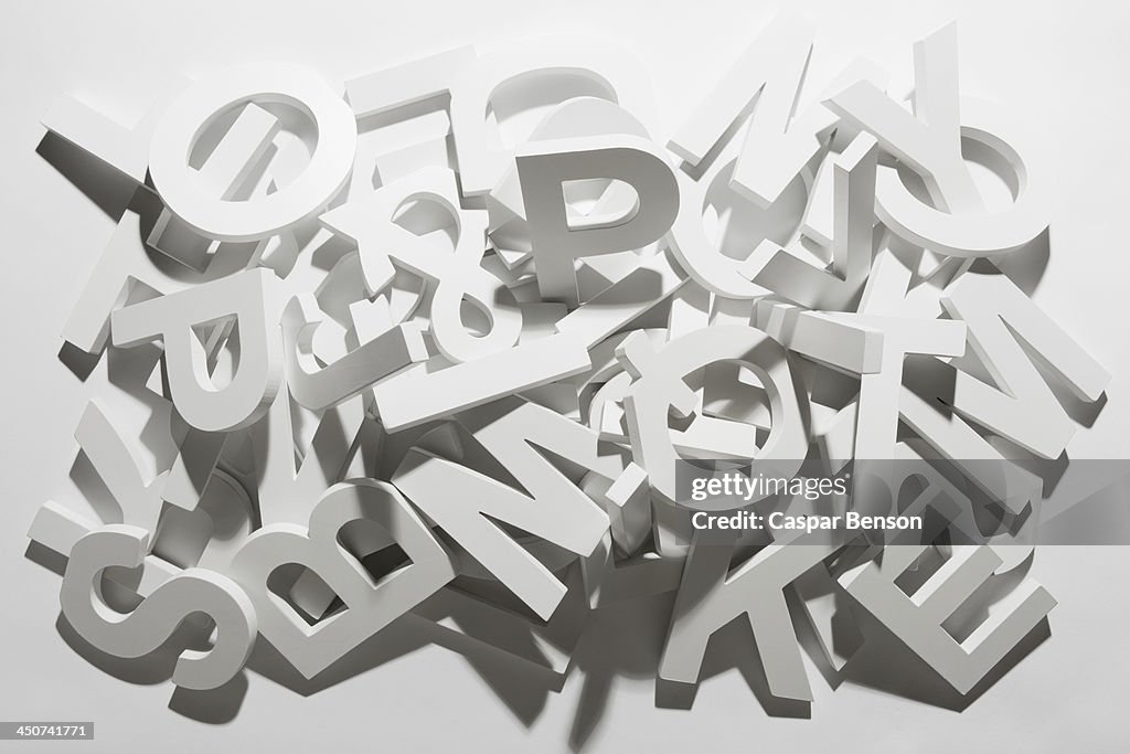 A pile of various white block letters from the alphabet