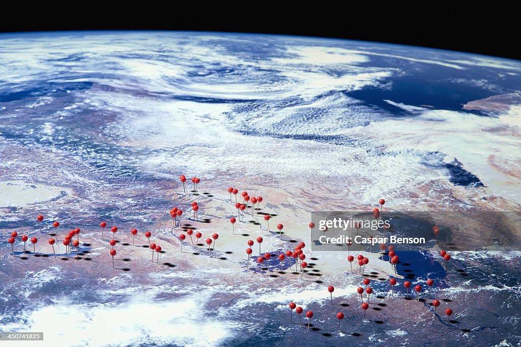 A satellite view of Earth with straight pins at various locations, digital composite