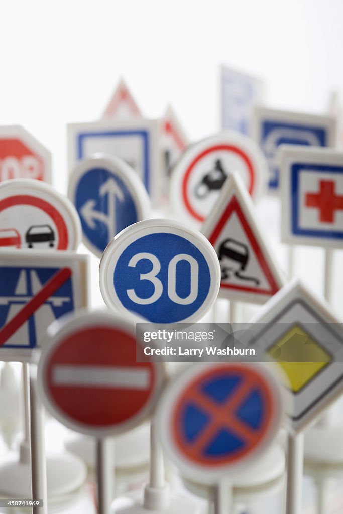 A toy speed limit sign surrounded by other various road warning signs