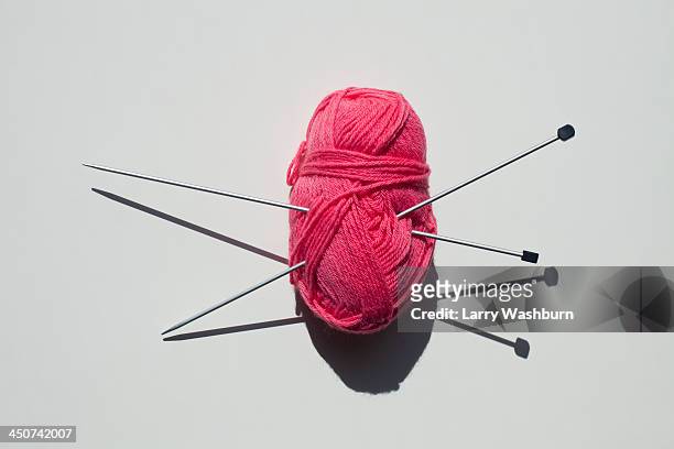 a pair of knitting needles stuck into a ball of yarn - lavorare a maglia foto e immagini stock