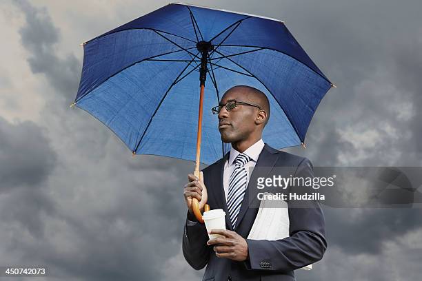 businessman holding umbrella, disposable coffee cup and newspaper under a moody sky - business people and paper imagens e fotografias de stock