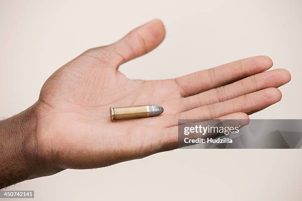 man holding out a single bullet - kogel stockfoto's en -beelden