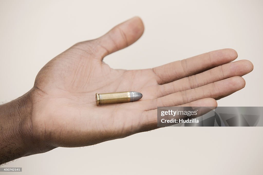 Man holding out a single bullet