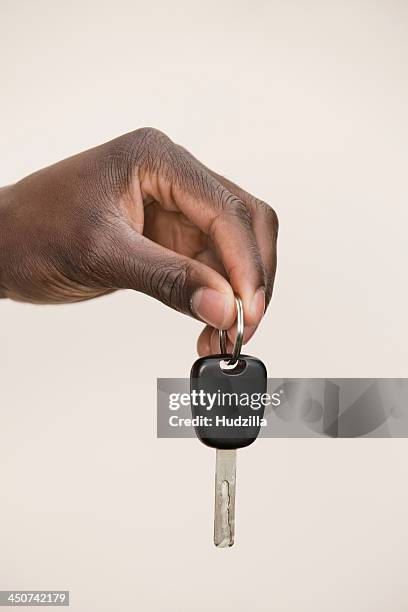 studio shot of man holding car key - car keys hand stockfoto's en -beelden