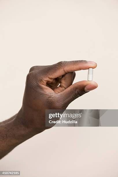 studio shot of man holding single capsule - piller bildbanksfoton och bilder