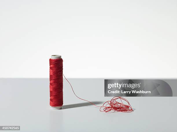 a spool of red thread with a pile of tangled thread - spool stock pictures, royalty-free photos & images