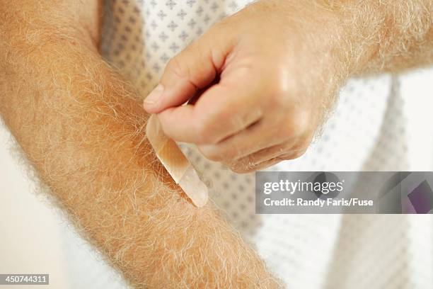 man peeling band-aid from arm - male hair removal stockfoto's en -beelden