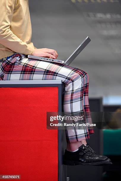 nerdy office worker with laptop sitting on cubicle wall - nerdy latina stock pictures, royalty-free photos & images