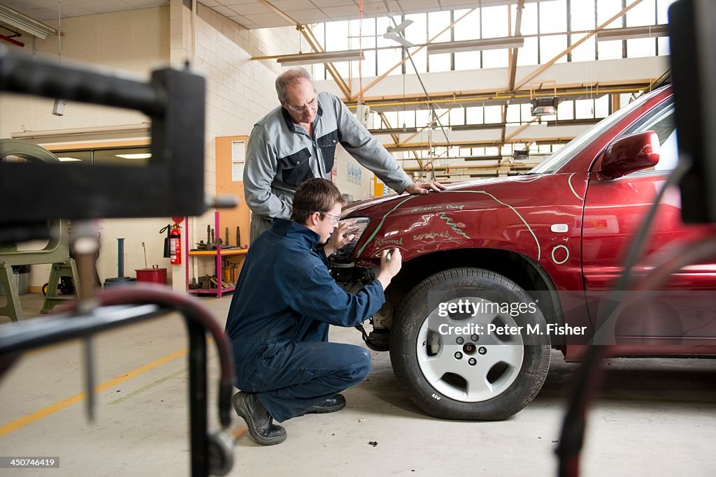 Mechanics checking damaged automobile