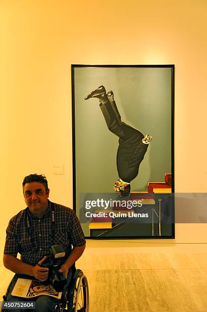 Photographer in a wheelchair passes in front of the painting 'Vestido bajando la escalera' of Eduardo Arroyo during the opening for the press of Pop...