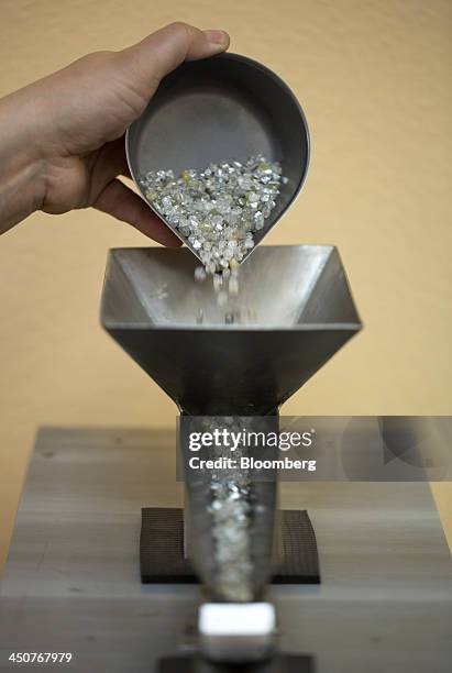 Worker loads a container of rough diamonds into an automatic sorting machine in the sorting center at OAO Alrosa's Mir diamond mine in Mirny, Russia,...
