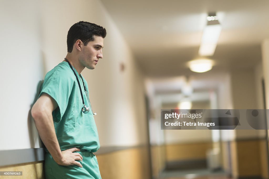 Tired doctor standing in hallway