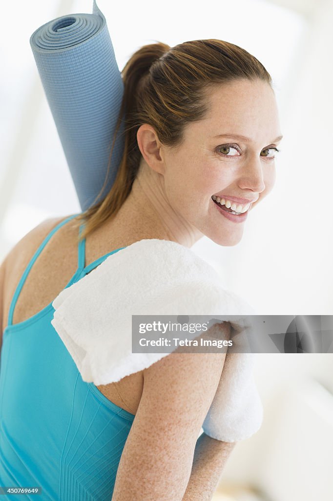 Woman carrying exercise mat and towel