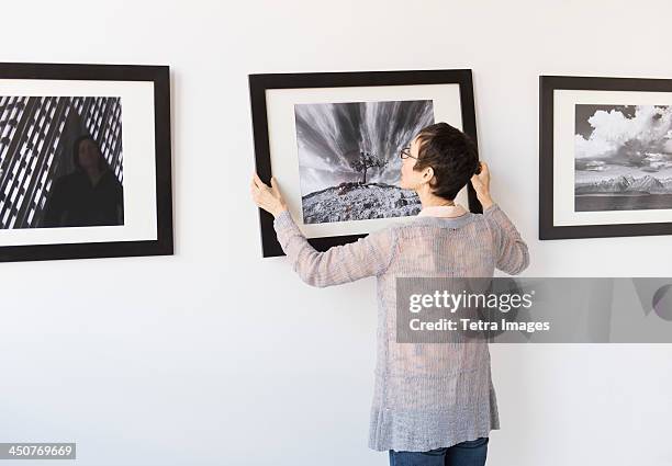 woman hanging photographs in art gallery - hanging photos stock pictures, royalty-free photos & images