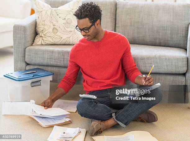 man sitting on floor in living room and calculating bills - tax man stock pictures, royalty-free photos & images