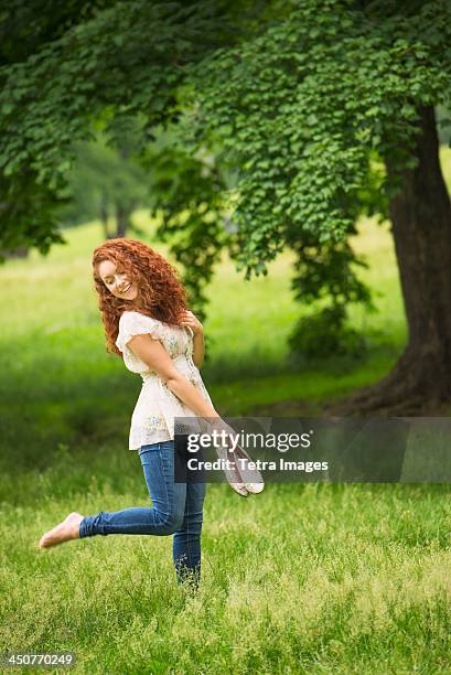 young woman walking in park - barefoot redhead ストックフォトと画像