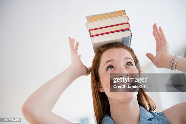 teenage girl (14-15) holding stack of books on head - 頭に乗せる ストックフォトと画像