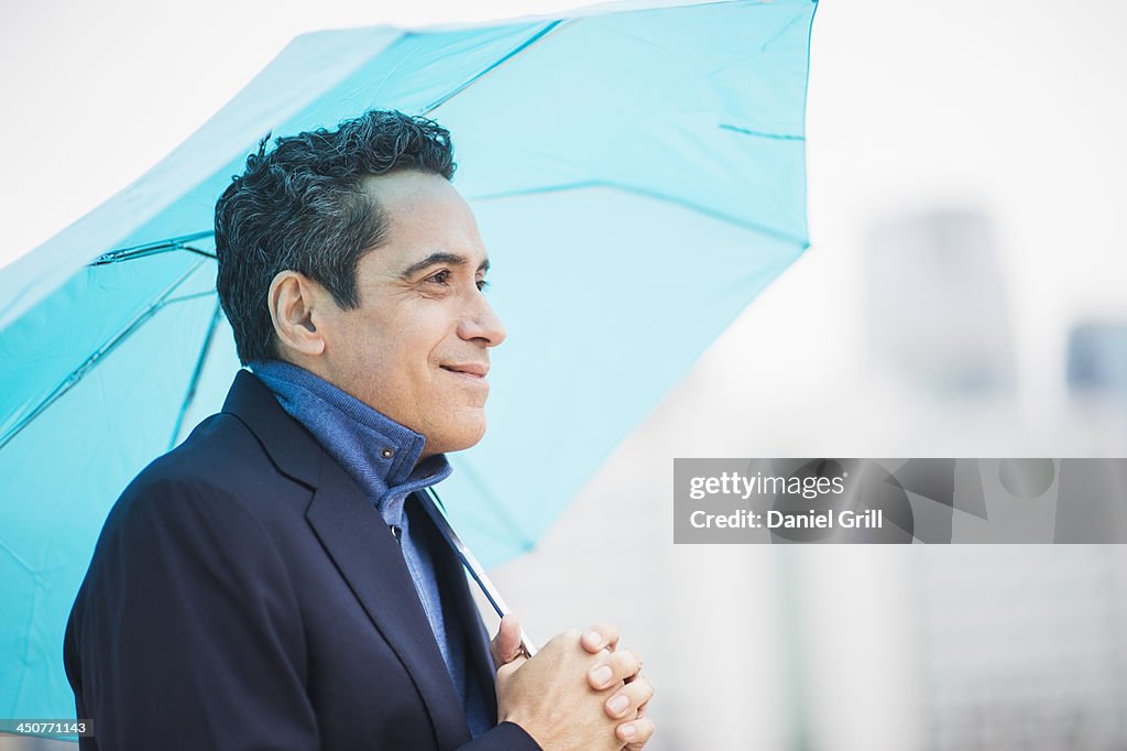 Portrait of man holding blue umbrella