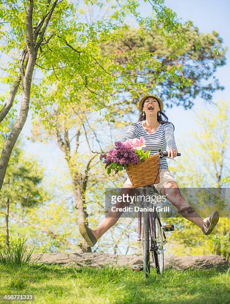mid adult woman riding bicycle - bicycle flowers stockfoto's en -beelden