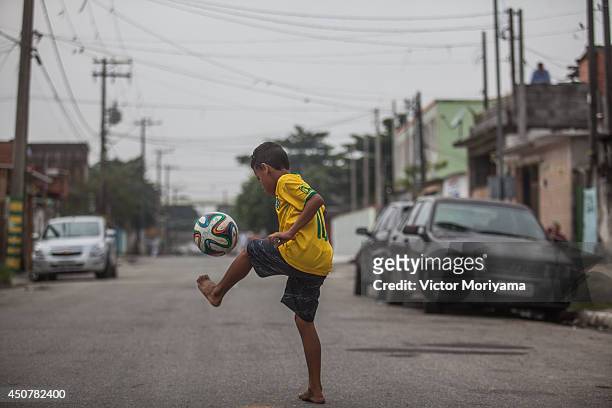 Boy plays soccer in the streets of the Garden Gloria neighborhood on June 17, 2014 in Praia Grande, Brazil. Soccer star Neymar of Brazil lived in...